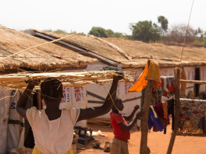 A South Sudanese refugee carries thatch through a Protection of Civilians site in South Sudan.