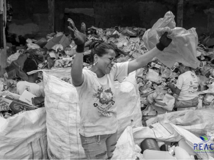 Photo of a woman dancing in front of a pile of trash.