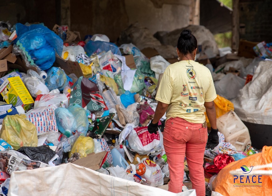 Photo of a woman sorting through a large pile of garbage. 