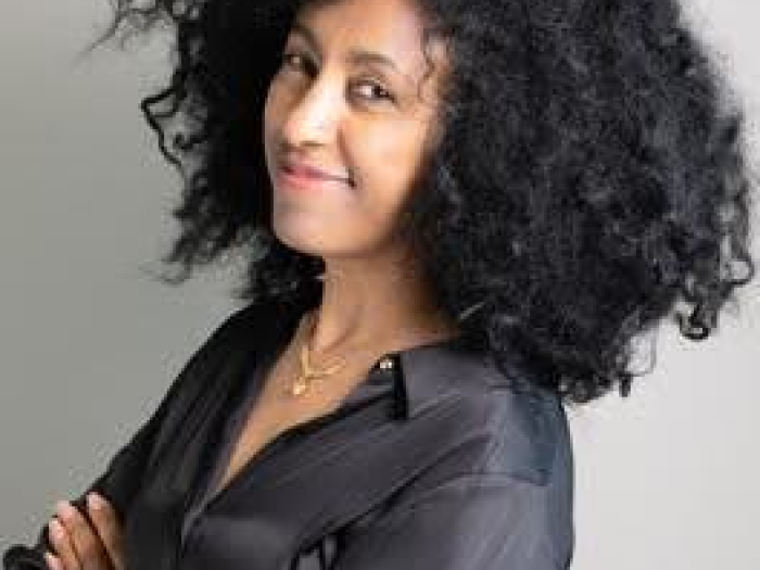 A woman is wearing a black shirt and posing for a professional headshot photograph. 