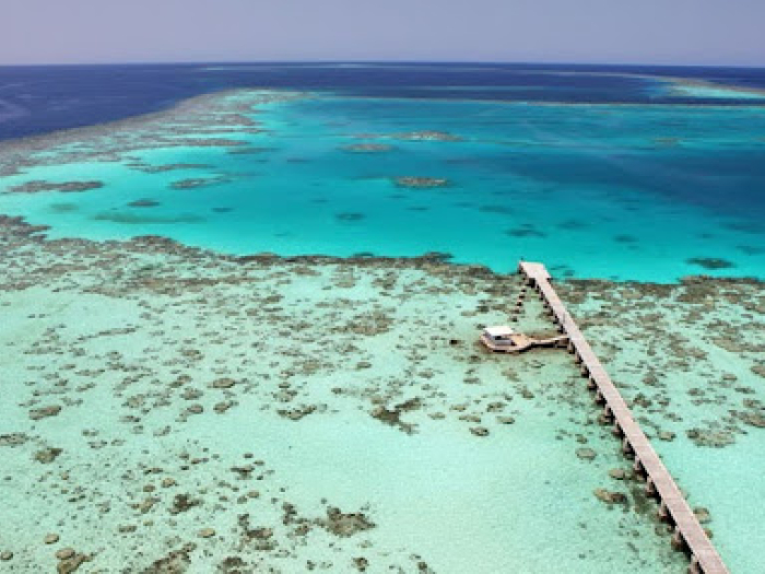 blue green ocean and a pier in the foreground of the picture. 