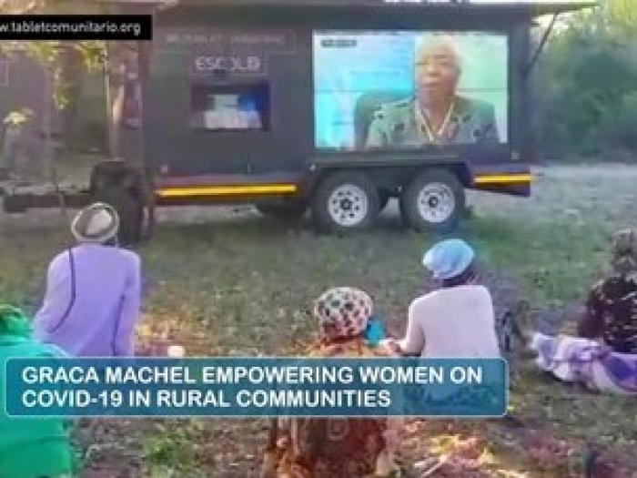 A photo of women sitting on the ground outside looking at a screen. Title text reads "Graca Machel Empowering Women on COVID-19 in Rural Communities"