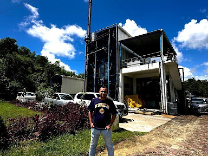 A man standing in front of a 2 story building. 
